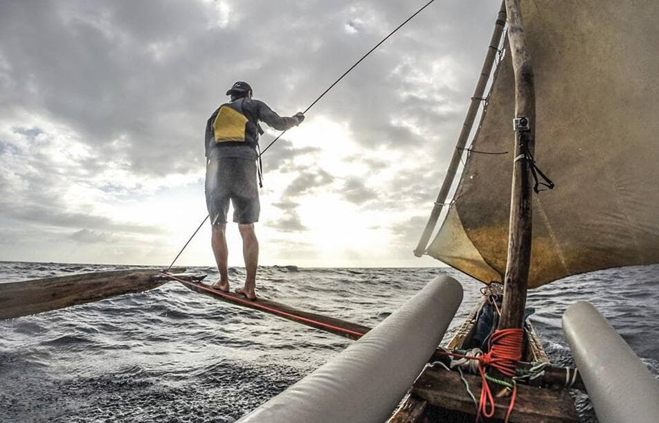 Jake standing on the outrigger of a mango tree sailboat off Tanzania